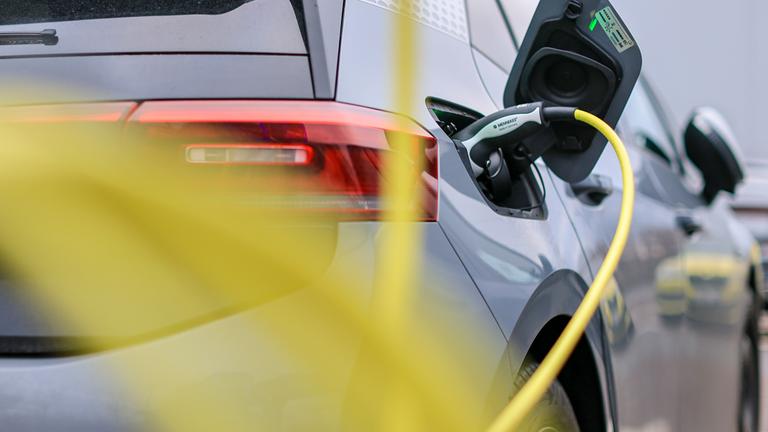 Ein Elektrofahrzeug von Volkswagen lädt mit einem gelben Kabel an einer Ladesäule. (Archiv)