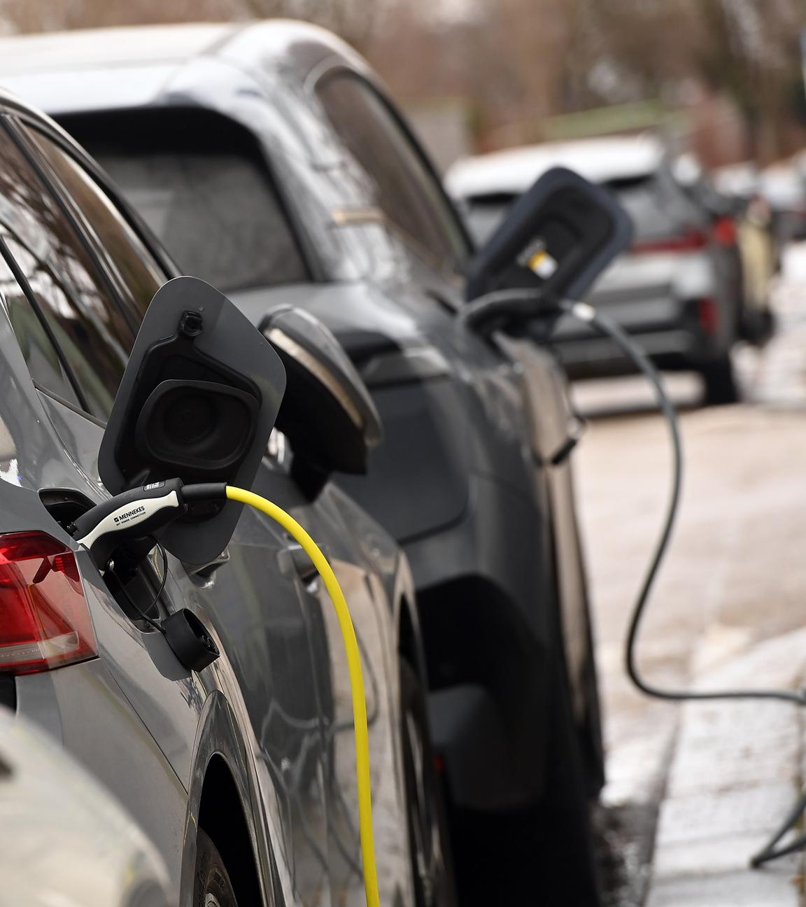 Zwei E-Autos werden auf einem Parkplatz für Elektro-Fahrzeuge geladen.