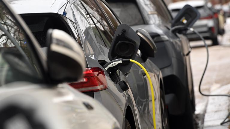 Zwei E-Autos werden auf einem Parkplatz für Elektro-Fahrzeuge geladen.