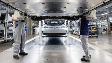 Mitarbeiter arbeiten am Unterboden mit der Batterie eines Elektrofahrzeugs von VW