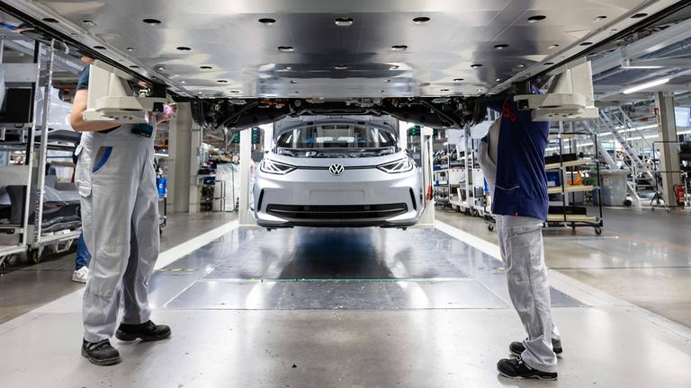 Mitarbeiter arbeiten am Unterboden mit der Batterie eines Elektrofahrzeugs von VW