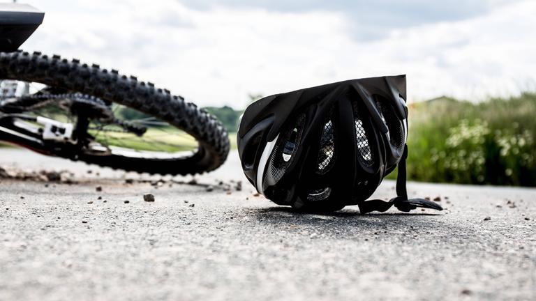 Ein Helm und ein Fahrrad liegen nebeneinander auf dem Boden.