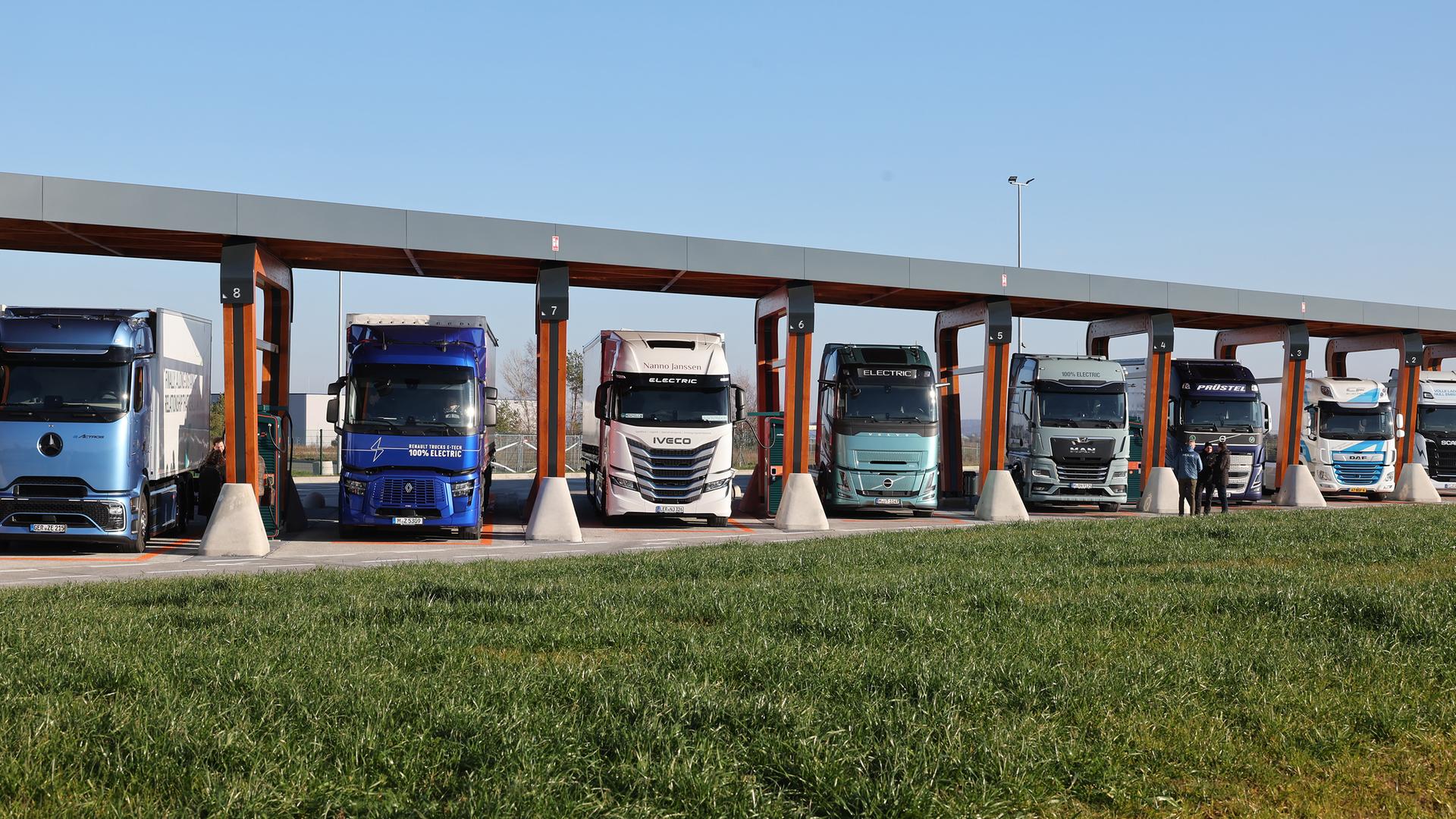 Lkw mit Elektroantrieb stehen in einer Ladebox eines Ladeparks für E-Lastwagen am Hermsdorfer Kreuz