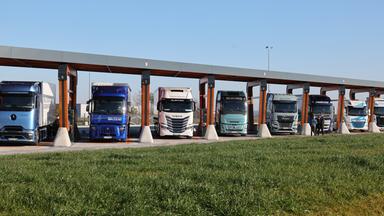 Lkw mit Elektroantrieb stehen in einer Ladebox eines Ladeparks für E-Lastwagen am Hermsdorfer Kreuz