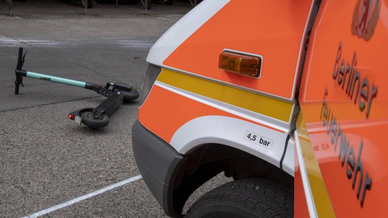 Ein auf der Straße liegender E-Roller vor einem Rettungswagen.