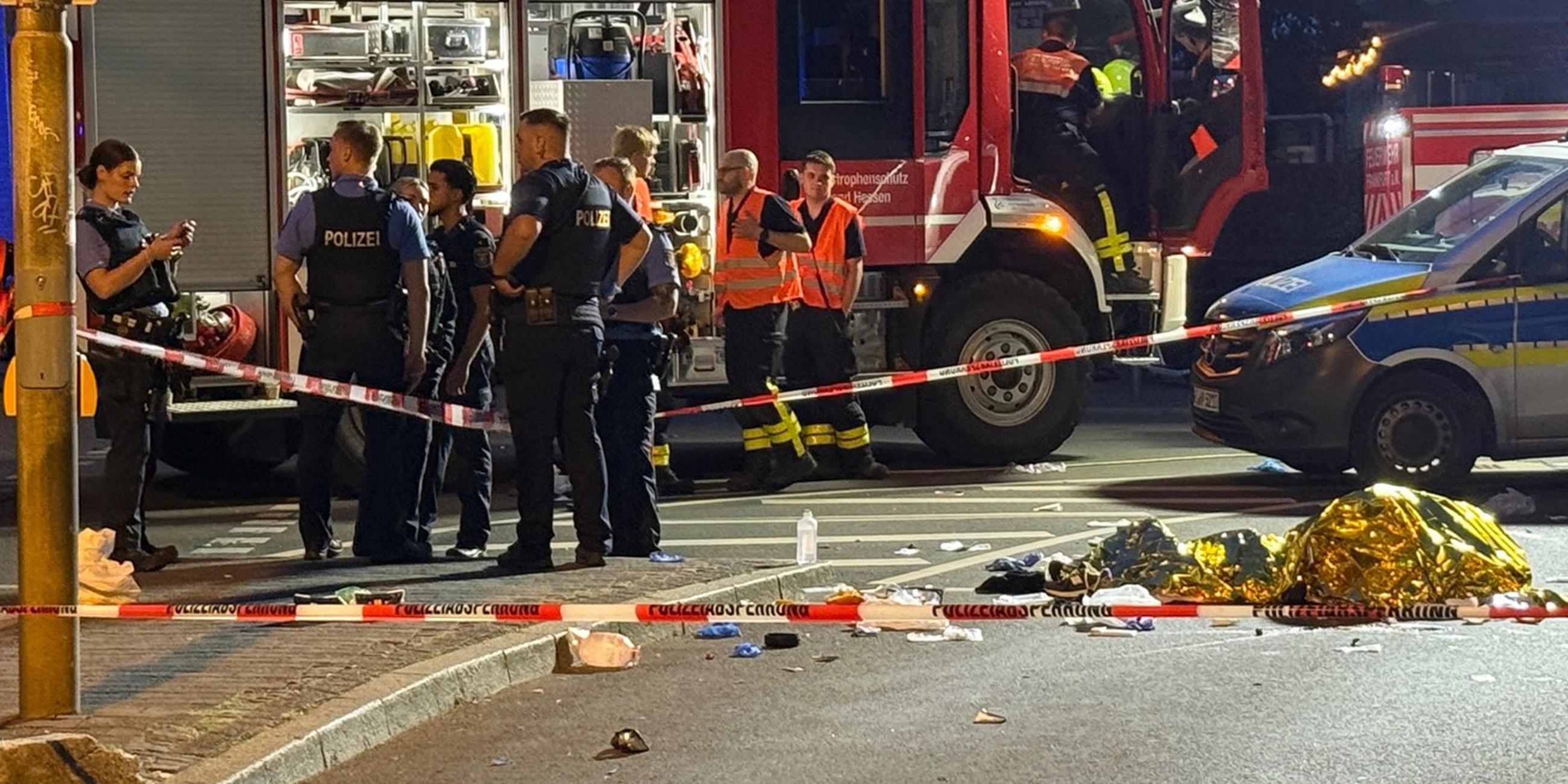  Einsatzkräfte der Polizei und Feuerwehr stehen am Unfallort an dem ein Autofahrer in der Nacht vom 06.07.2025 eine Person auf einem E-Scooter erfasst.