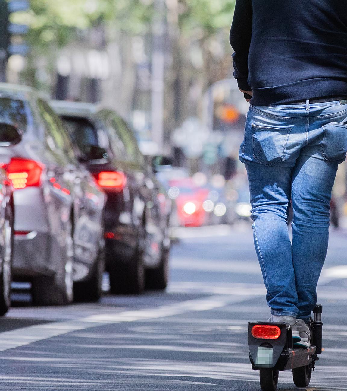 Ein Mann fährt auf dem Fahrradweg mit einem E-Scooter über den Kölner Ring Ein Mann fährt auf dem Fahrradweg mit einem E-Scooter über den Kölner Ring