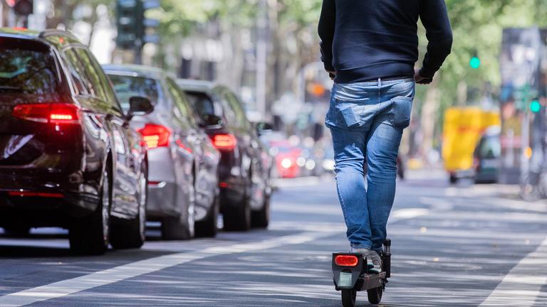 Ein Mann fährt auf dem Fahrradweg mit einem E-Scooter über den Kölner Ring Ein Mann fährt auf dem Fahrradweg mit einem E-Scooter über den Kölner Ring