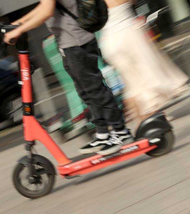 Symbolbild: Ein Mann fährt mit einem E-Scooter über den Vorplatz vom Hauptbahnhof Köln.