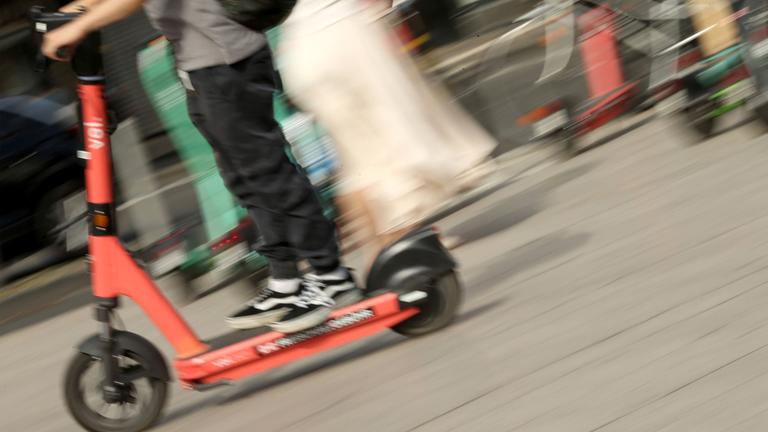 Symbolbild: Ein Mann fährt mit einem E-Scooter über den Vorplatz vom Hauptbahnhof Köln.
