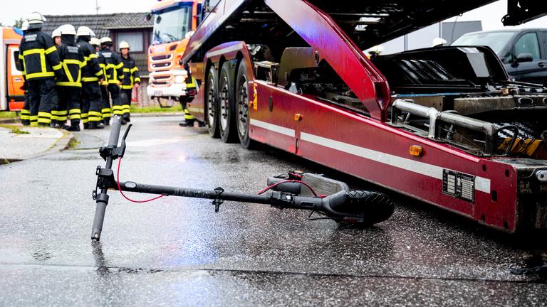  Ein E-Roller liegt an einer Unfallstelle neben einem Lastwagen. 