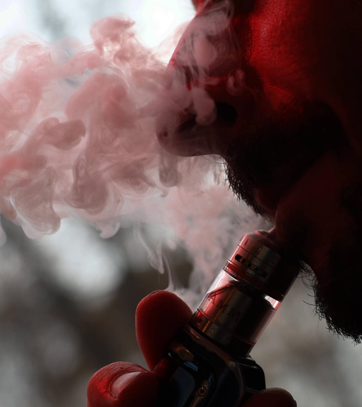 Ein Mann bläst den Rauch einer E-Zigarette aus.