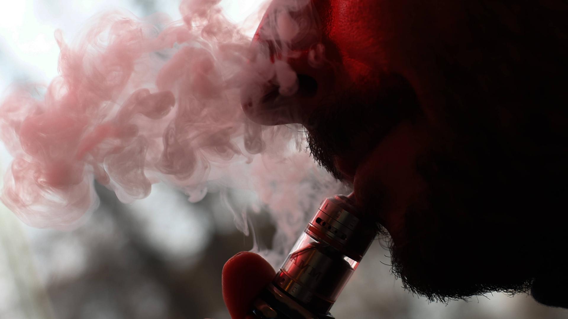 Ein Mann bläst den Rauch einer E-Zigarette aus.