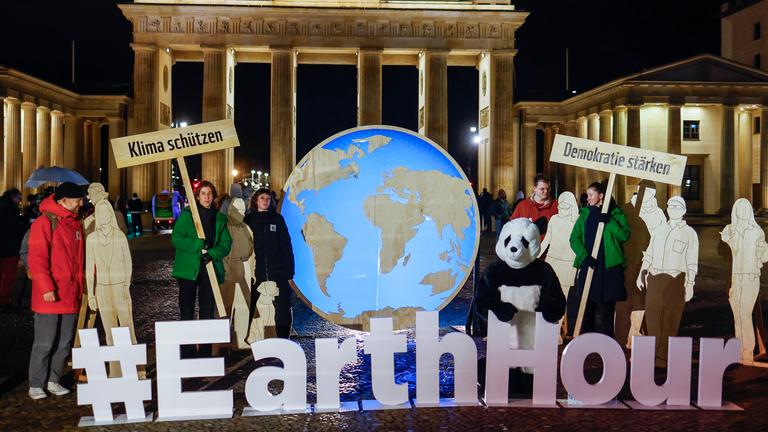 Aktivisten stehen während der "Earth Hour" vor dem Brandenburger Tor in Berlin