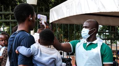 Ein Gesundheitsbeamter untersucht Menschen mit einem Thermometer vor dem Kibuli Muslim Hospital in Kampala.