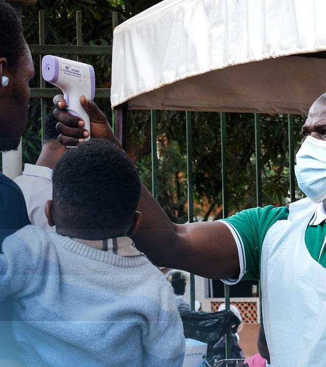 Ein Gesundheitsbeamter untersucht Menschen mit einem Fieberthermometer in Kampala, Uganda.