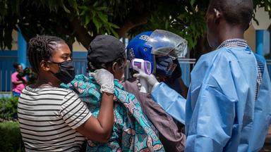 Ein Gesundheitsmitarbeiter (r.) misst die Temperatur eines Patienten (2. v. l.), bei dem der Verdacht auf Ebola besteht.