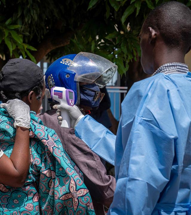 Ein Gesundheitsmitarbeiter (r.) misst die Temperatur eines Patienten (2. v. l.), bei dem der Verdacht auf Ebola besteht.