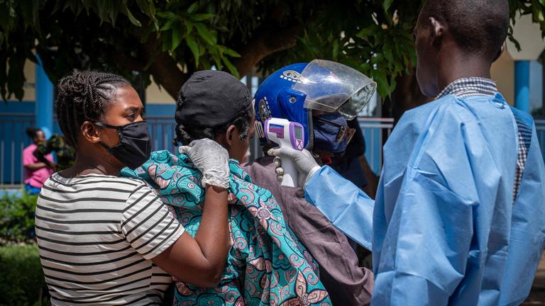 Ein Gesundheitsmitarbeiter (r.) misst die Temperatur eines Patienten (2. v. l.), bei dem der Verdacht auf Ebola besteht.