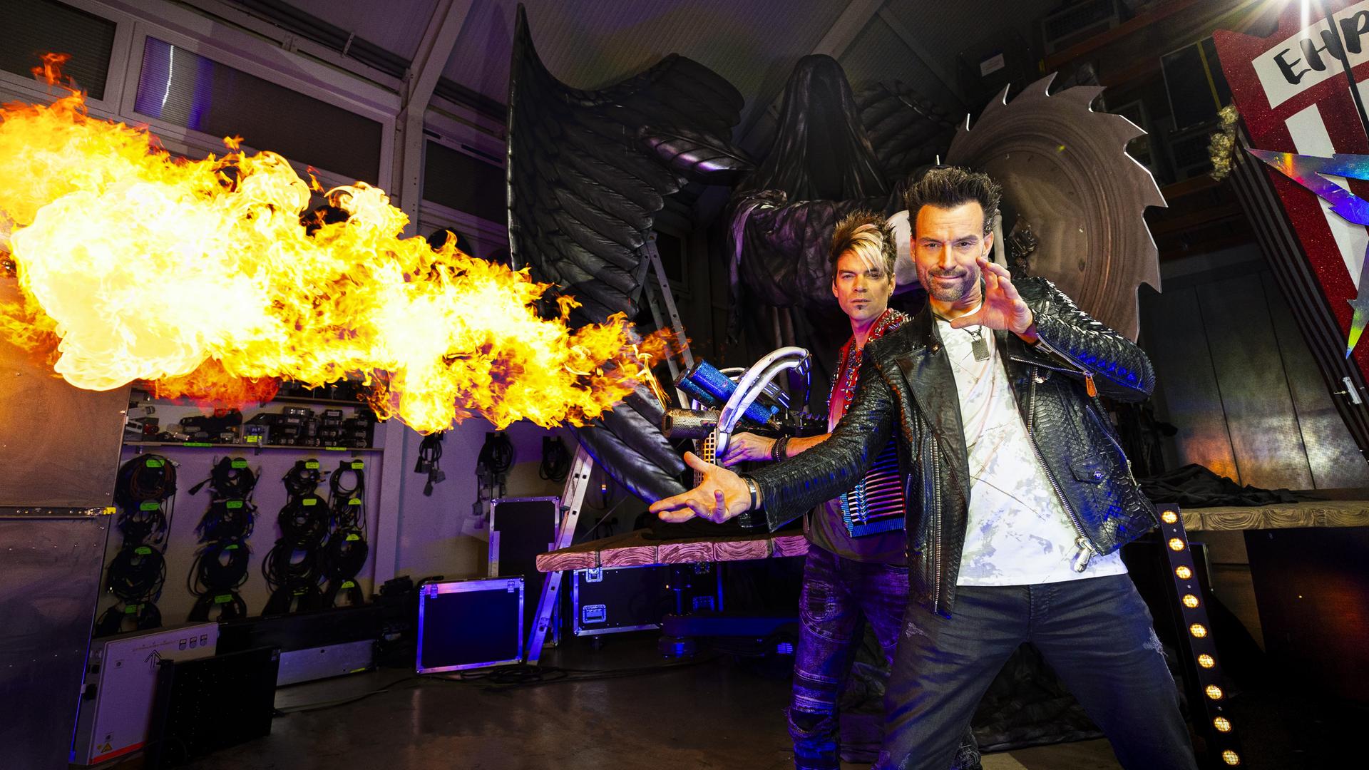 Backstage: Das Magierduo Ehrlich Brothers steht neben feuriger Pyrotechnik.
