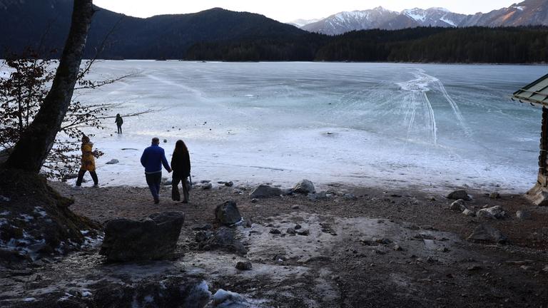 Ausflügler laufen am Ufer des zugefrorenen Eibsees, nahe der Stelle an der am Nachmittag mehrere Menschen im Eis eingebrochen waren. 
