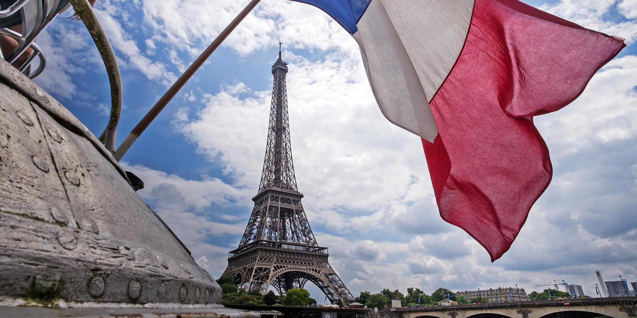 Die französische Flagge weht am heck eines Schiffes vor dem Eiffelturm in Paris (Frankreich)