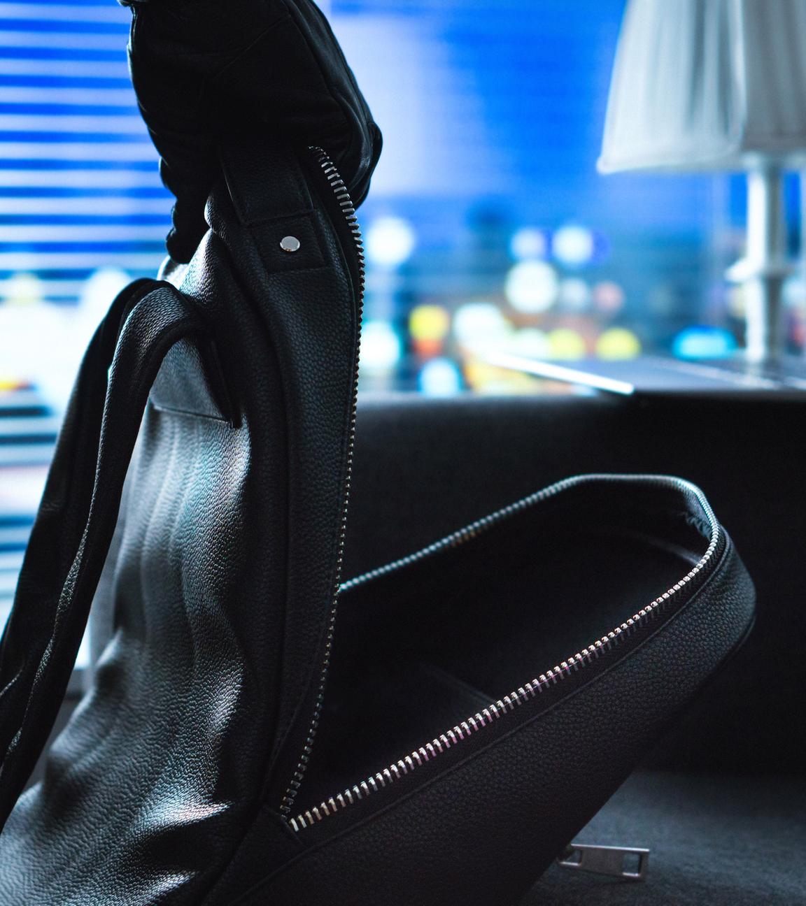 Offener Rucksack in einem Zimmer, Laptop im Hintergrund