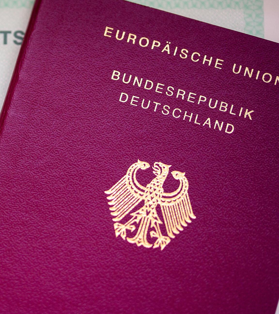 Eine Einbürgerungsurkunde der Bundesrepublik Deutschland (l) und ein deutscher Reisepass liegen auf einem Tisch