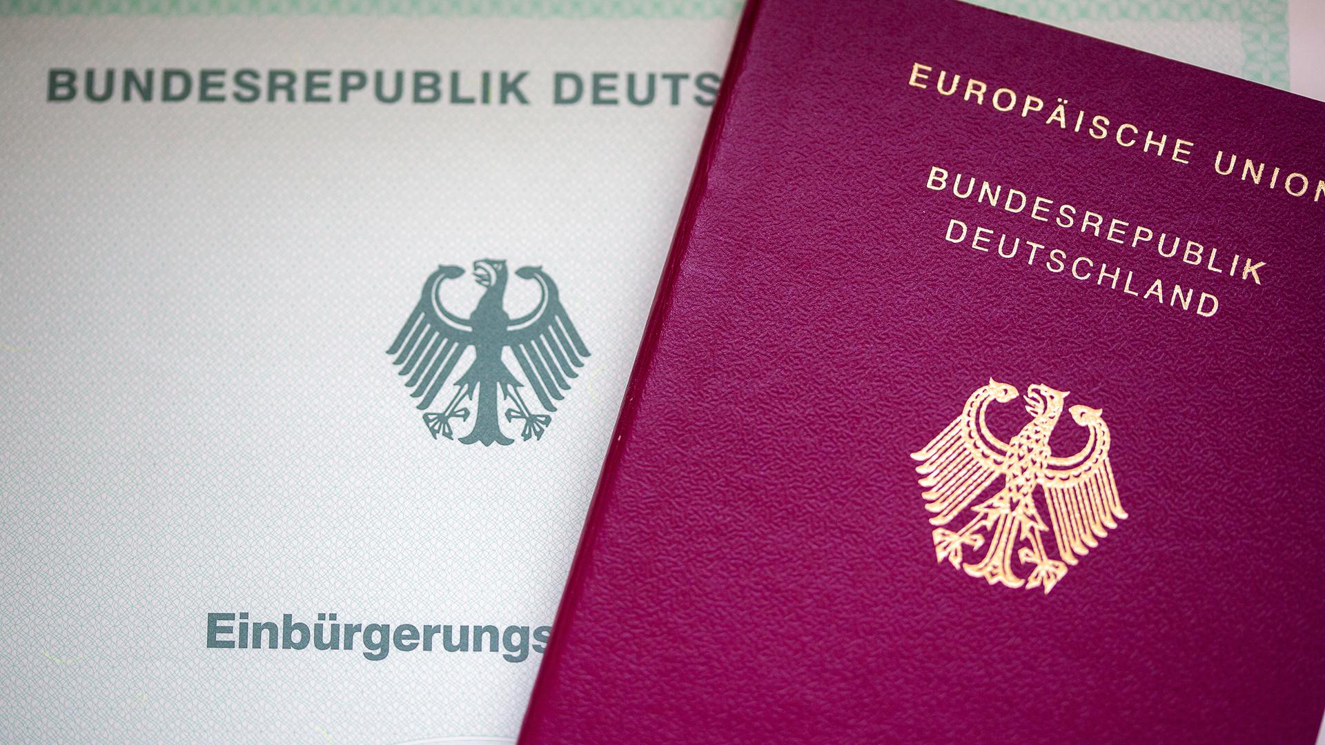 Eine Einbürgerungsurkunde der Bundesrepublik Deutschland (l) und ein deutscher Reisepass liegen auf einem Tisch