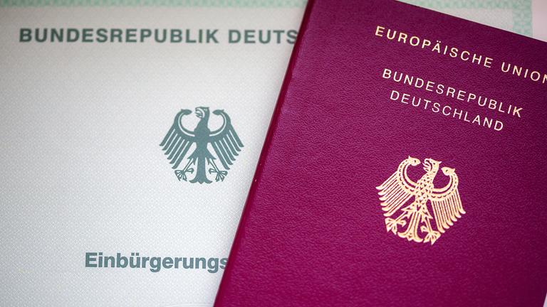 Eine Einbürgerungsurkunde der Bundesrepublik Deutschland (l) und ein deutscher Reisepass liegen auf einem Tisch