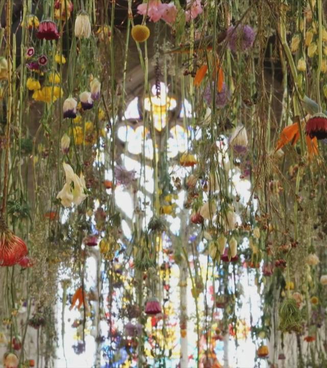 Sehr viele Blumen hängen von der Decke einer Kirche