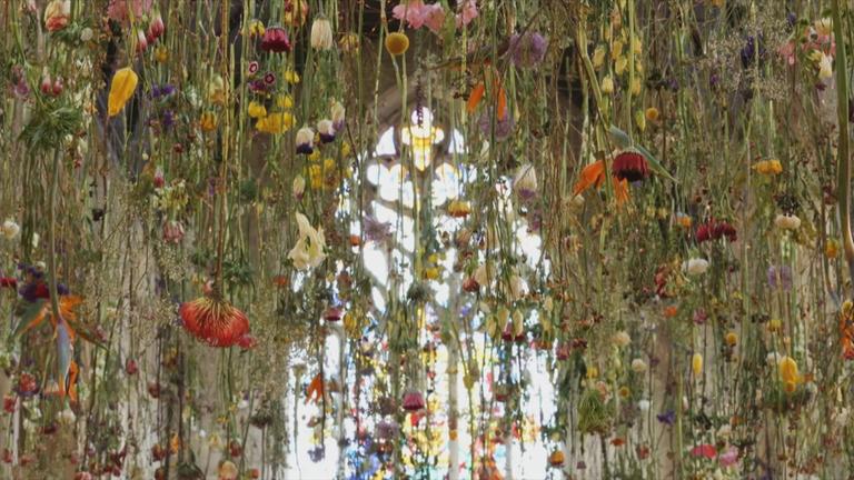 Sehr viele Blumen hängen von der Decke einer Kirche