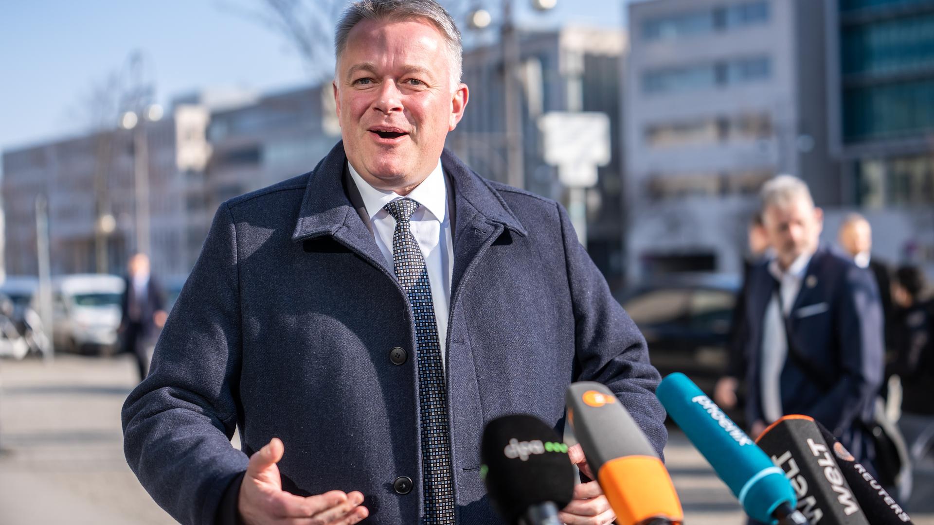 Gordon Schnieder freut sich und spricht in einige Mikrofone. 