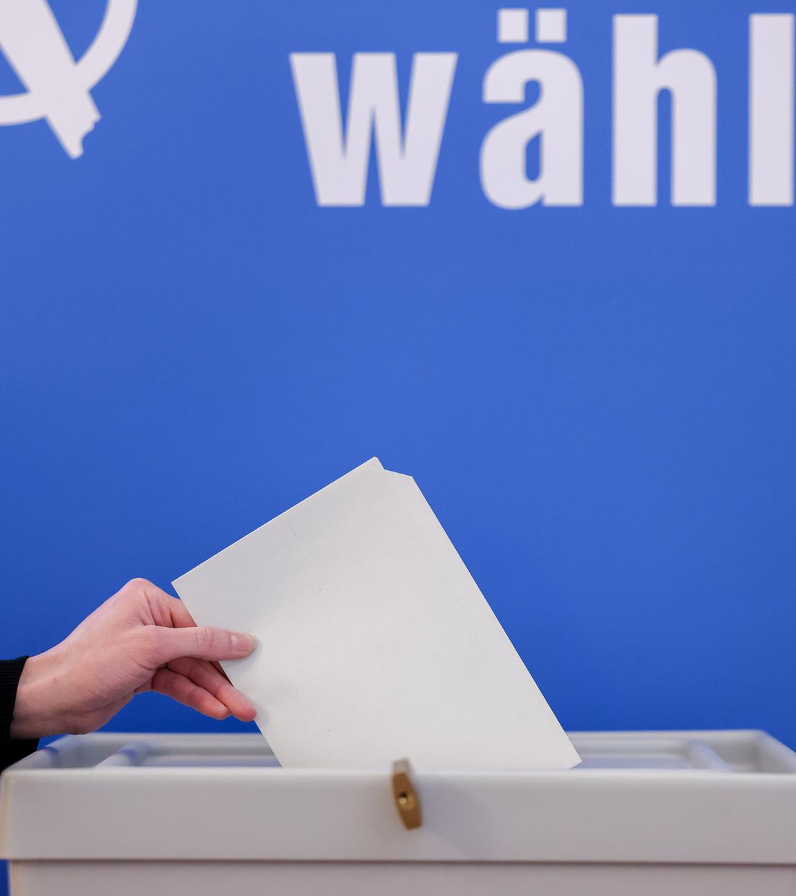 Ein Wahlzettel wird in eine Wahlurne gesteckt.