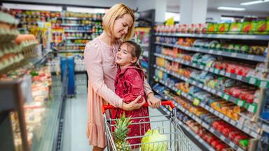 Mutter tröstet ihre aufgebrachte Tochter beim Einkaufen im Supermarkt.