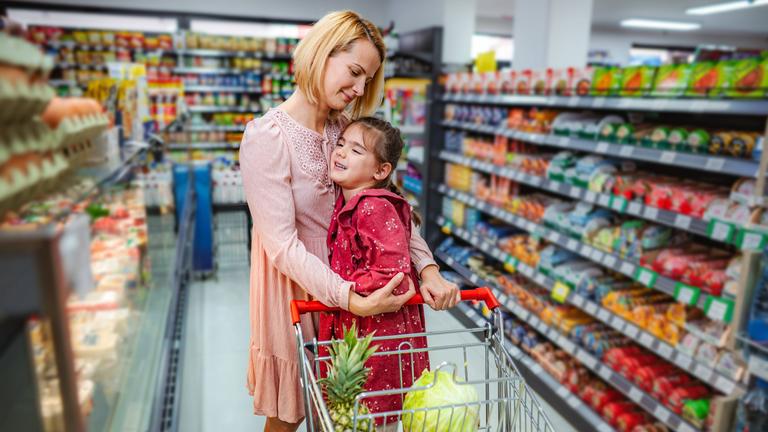 Mutter tröstet ihre aufgebrachte Tochter beim Einkaufen im Supermarkt.