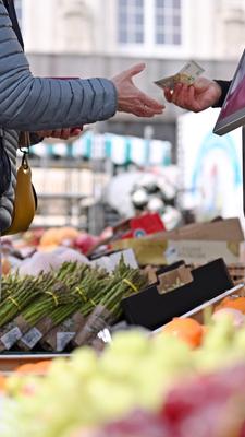Eine Frau erhält Rückgeld an einem Marktstand in Leipzig.