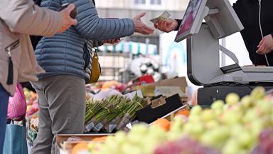 Eine Frau erhält Rückgeld an einem Marktstand in Leipzig.