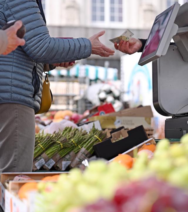 Eine Frau erhält Rückgeld an einem Marktstand in Leipzig.