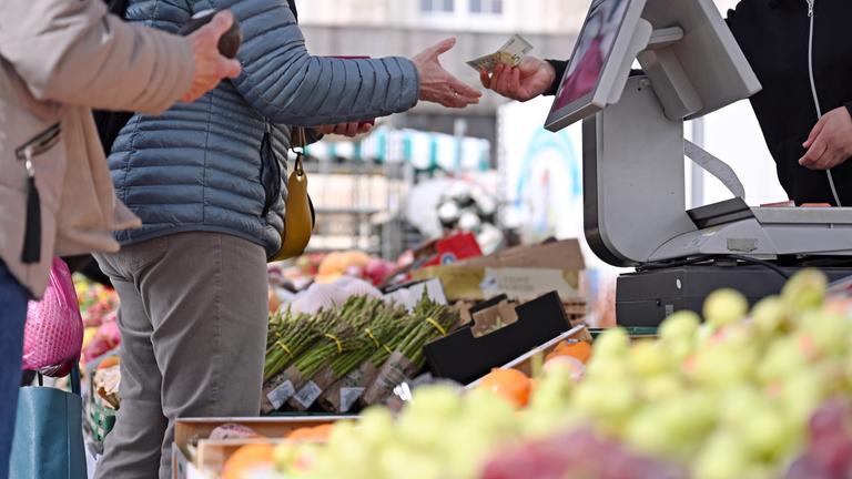 Eine Frau erhält Rückgeld an einem Marktstand in Leipzig.