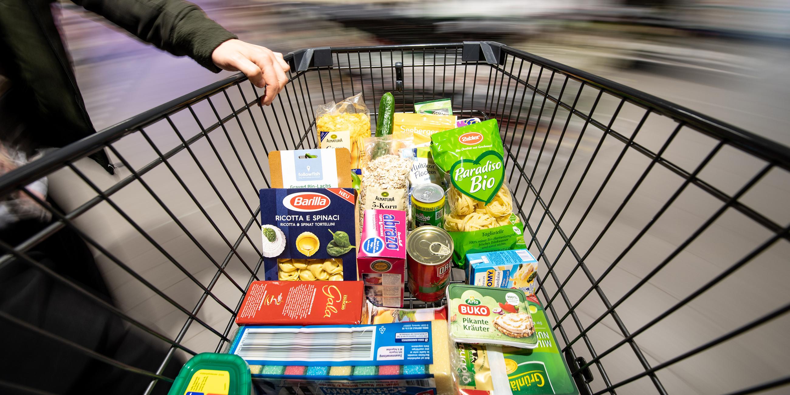 Einkaufswagen mit unterschiedlichen Lebensmitteln in Verpackungen