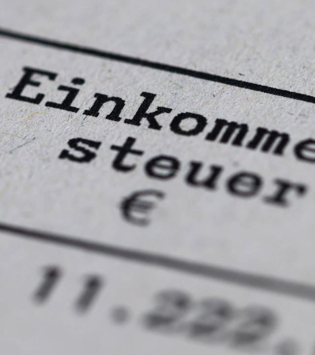 Ein Steuerbescheid mit dem Vermerk "Einkommensteuer" liegt auf einem Tisch.