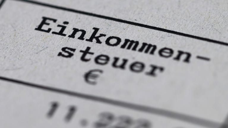 Ein Steuerbescheid mit dem Vermerk "Einkommensteuer" liegt auf einem Tisch.