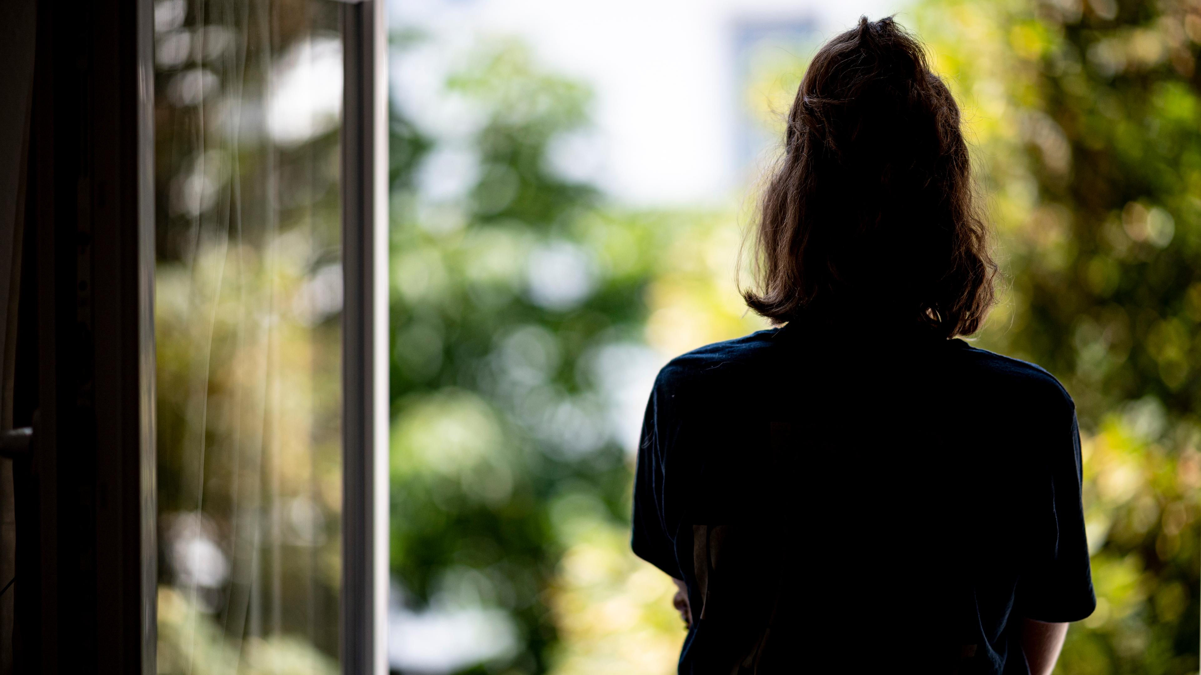 Einsame Frau steht am offenen Fenster