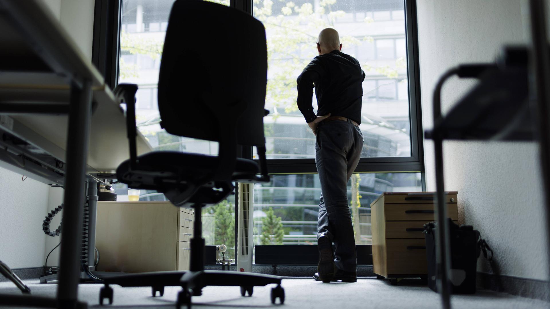 Ein Mann schaut aus dem Bürofenster.
