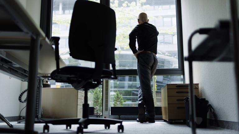 Ein Mann schaut aus dem Bürofenster.