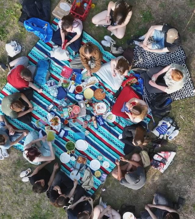Eine Gruppe junger Menschen auf einer Picknick-Decke aus der Vogelperspektive