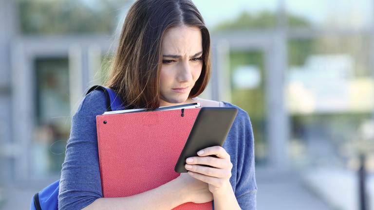 Traurige Studentin schaut in ihr Smartphone