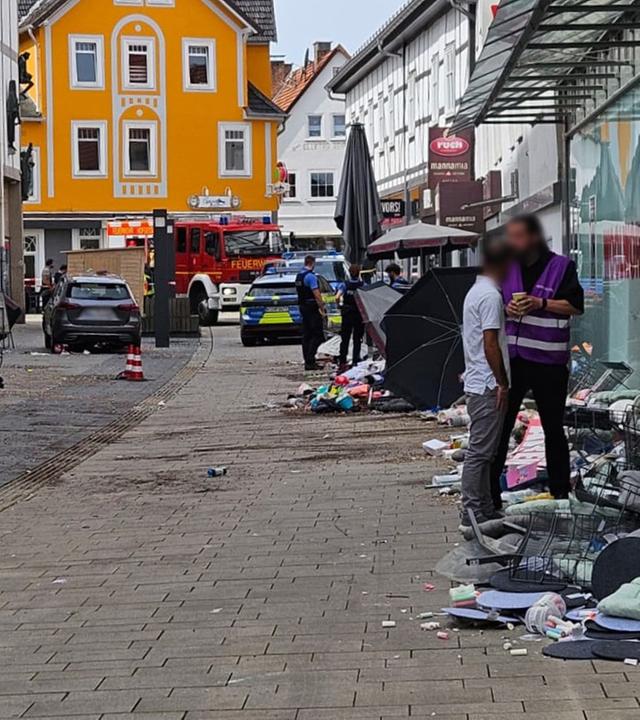 Einsatzkräfte stehen in der Stadt nachdem am 21.08.2026 im hessischen Hofgeismar ein Auto gegen die Hauswand eines Kaufhauses gefahren ist.