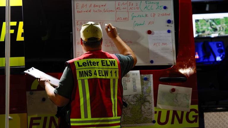 Ein Feuerwehrmann schreibt in der Einsatzleitstelle Informationen auf ein Board am 17.08.2026 in Monschau, Nordrhein-Westfalen.